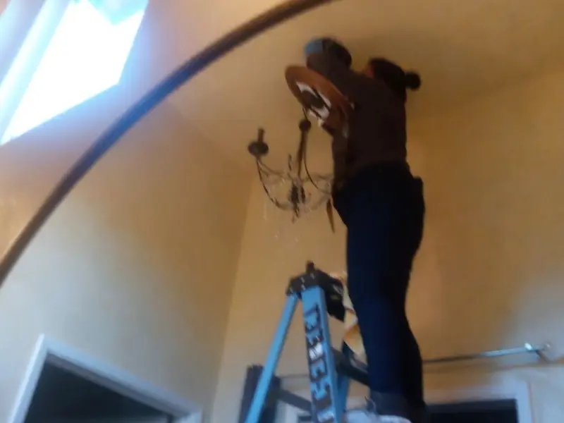Electrician installing a chandelier in a Harris residence